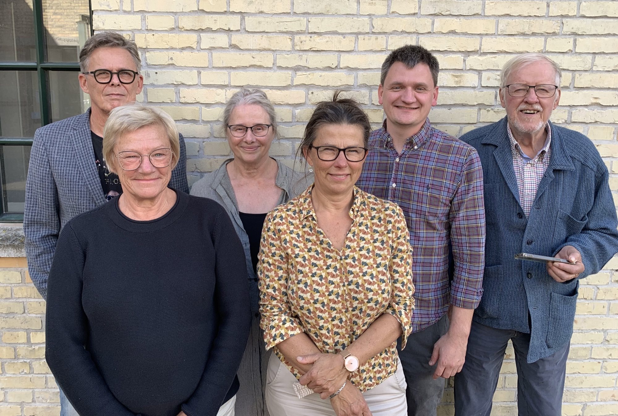 ARTIGs seks bestyrelsesmedlemmer samlet foran en lys mur
